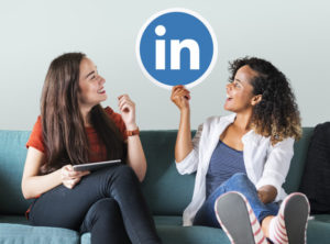 Use of linkedIn. Two girls holding a LinkedIn Logo.