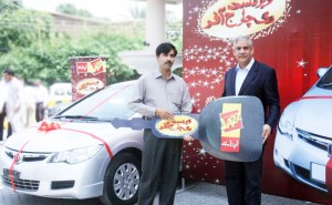 Irfan Akram, Vice President Customer Care, Mobilink presenting Muhammad Ihsan Ul Haq, one of the winners of the Jazz Zabardast Recharge offer, the keys of the 1,800 cc car. 