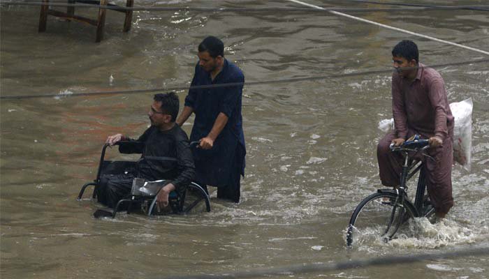 Man on wheelchair at flooded lahore road